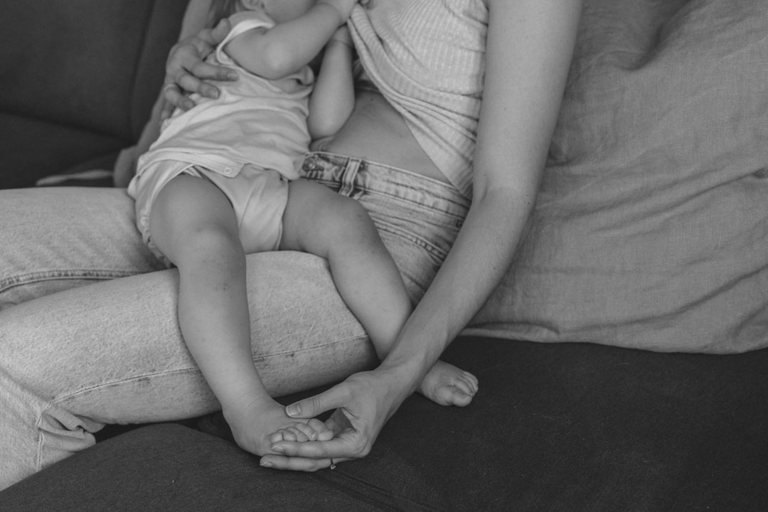 Mutter stillt ihr Baby und hält liebevoll den kleinen Fuß fest.