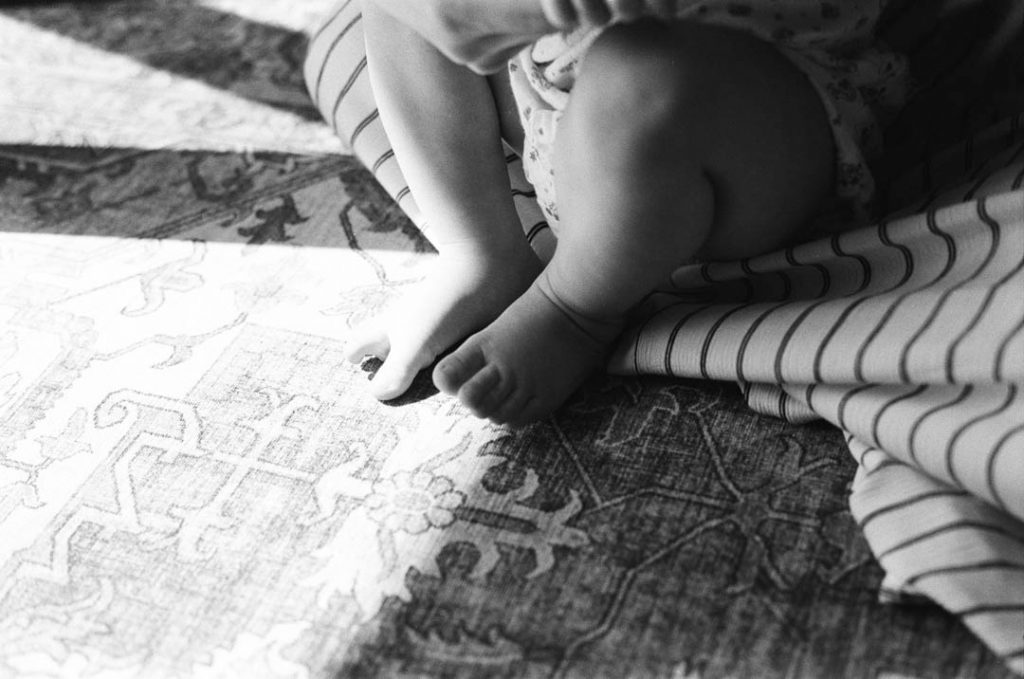 Babyfüße in der Sonne, aufgenommen in Schwarzweiß.